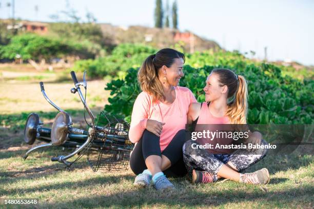 mother and daughter sitting next to the tandem bike - hawaii vacation and parent and teenager stock pictures, royalty-free photos & images