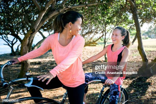 close-up of mother and daughter on a tandem bike - hawaii vacation and parent and teenager stock pictures, royalty-free photos & images