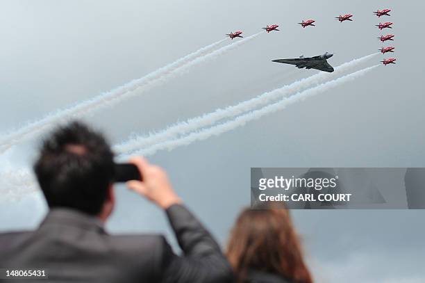 The Red Arrows fly in formation alongside a Vulcan bomber to officially open the Farnborough International Airshow in Hampshire, southern England, on...