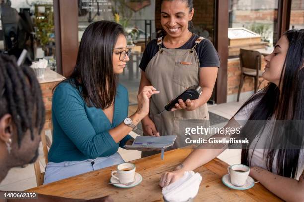 waitress accepting payment by card at coffee shop - card reader stockfoto's en -beelden