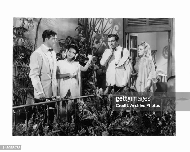 John Payne stares at Alice Faye as they stand with Don Ameche, who holding his hand against his cheek, and Carmen Miranda in a scene from the film...