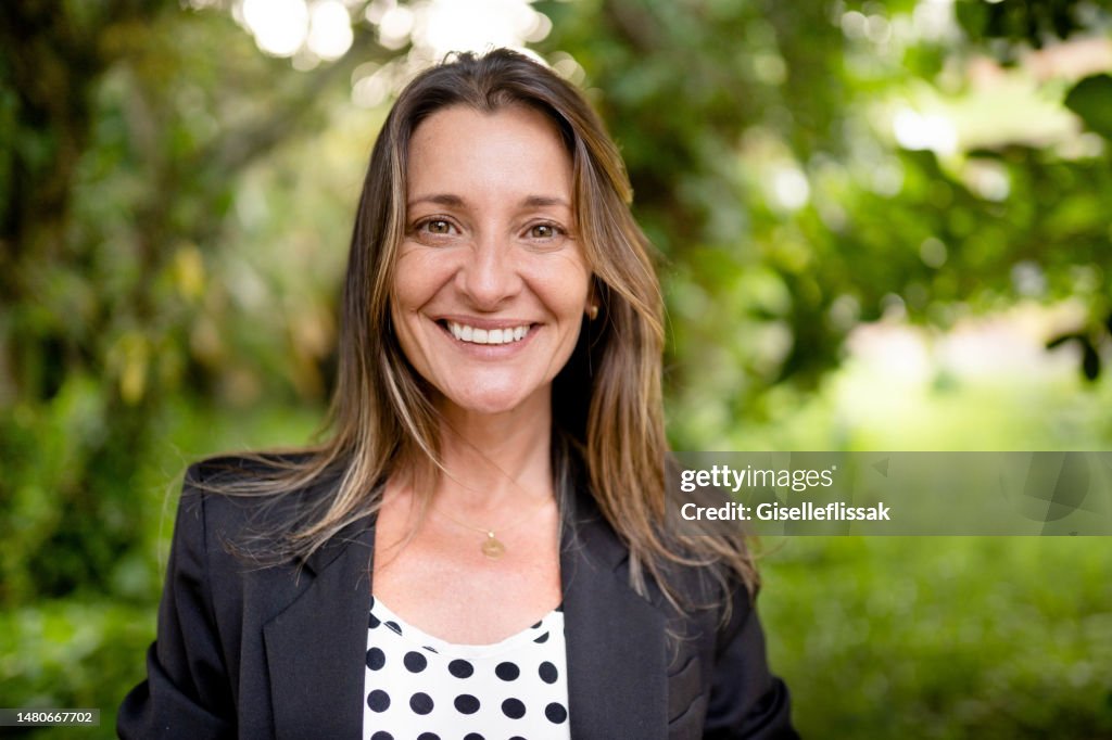 Mature woman standing outside in a park and smiling