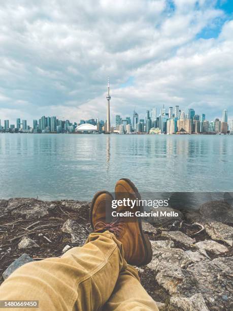 pov of man legs by lake ontario and views of toronto - lake ontario stock-fotos und bilder