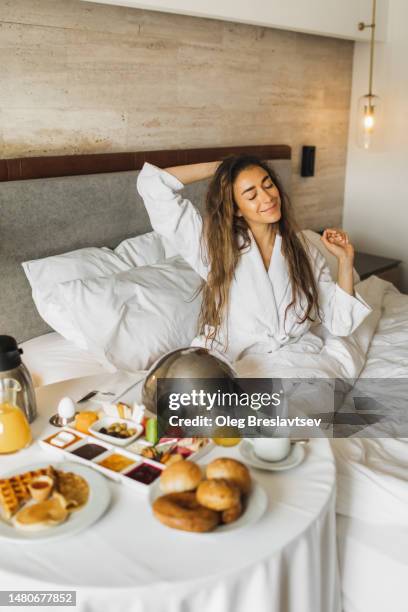 happy woman waking up in hotel and have tasty fresh breakfast served in room - robe stock pictures, royalty-free photos & images