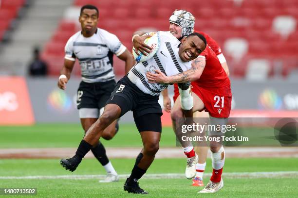 Waisea Nacuqu of Fiji is tackled by Max Stewart of Canada in their pool match during the HSBC Singapore Rugby Sevens at the National Stadium on April...