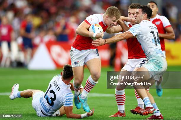 Freddie Roddick of Great Britain fends off a tackle by Marcos Moneta and Joaquin Pellandini of Argentina in their pool match during the HSBC...