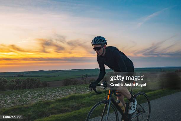 cyclist on a country road at sunset - fahrradlampe stock-fotos und bilder