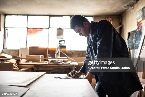 young carpenter making annotations on his clipboard at carpentry - man with clipboard and pencil stock pictures, royalty-free photos & images