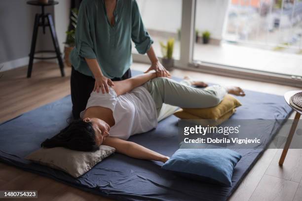 woman lying on side and having one side of her upper body stretched - shiatsu stock pictures, royalty-free photos & images