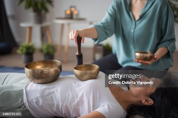 une femme allongée sur le dos pendant les bols chantants tibétains médite profondément et message - tibet stock photos et images de collection