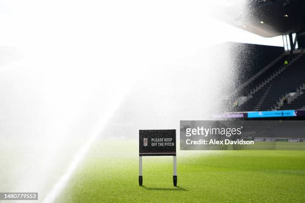 Sign reading "Keep please off the pitch" is seen as sprinklers water the pitch prior to the Premier League match between Fulham FC and West Ham...