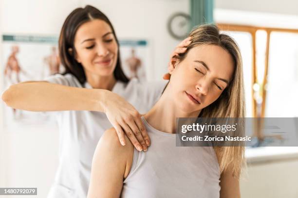 une jeune femme au programme de physiothérapie ressent une douleur au cou - kinésithérapie photos et images de collection