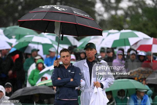 Justin Thomas of the United States and his caddie Jim 'Bones' Mackay react to his bogey on the 18th green during the continuation of the weather...