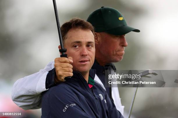 Justin Thomas of the United States and his caddie Jim 'Bones' Mackay react to his bogey on the 18th green during the continuation of the weather...