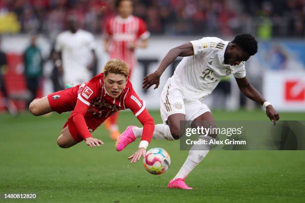 Ritsu Doan of SC Freiburg clashes with Alphonso Davies of Bayern Munich during the Bundesliga match between Sport-Club Freiburg and FC Bayern München...