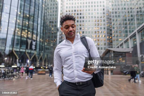 mixed race man with out from the office walking while looking at his cellphone - positive emotion stock pictures, royalty-free photos & images