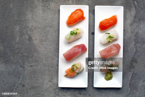 a sushi platter with fresh fish and rice arranged carefully on the dish with garnishes - nigiri stockfoto's en -beelden
