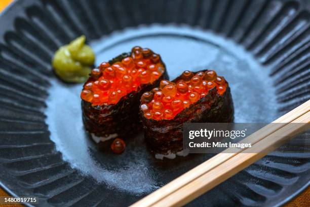 a dish with two portions of sushi, rice wrapped in seaweed with fish roe - fusion food stock pictures, royalty-free photos & images