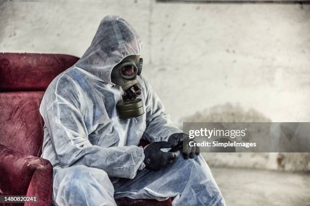 man wearing gas mask, protective wear and gloves in industrial environment to protect against threats. - radiation sickness stock pictures, royalty-free photos & images