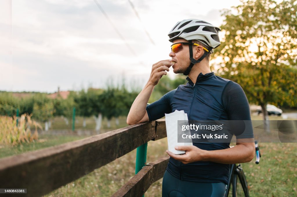 Professional cyclist in cycling gear taking a break and eating a snack