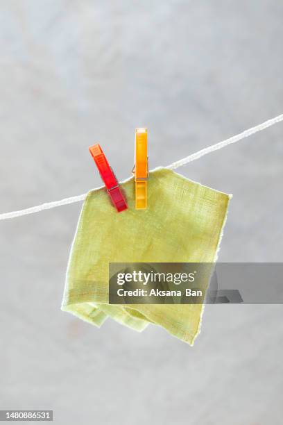 light green linen napkin on a clothesline with red and orange clothespins. close-up - handkerchief stock pictures, royalty-free photos & images