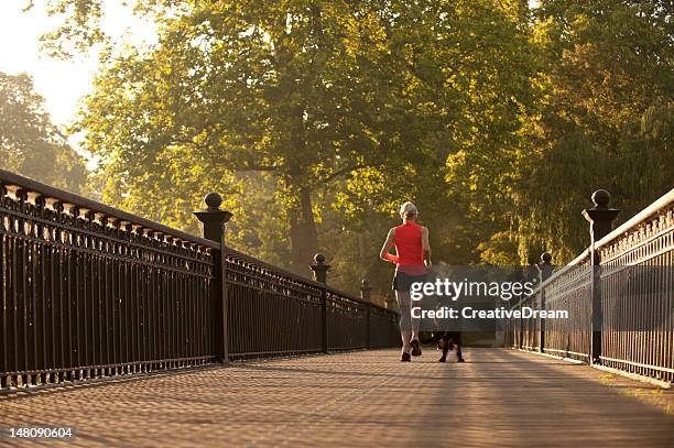 woman running in park with dog - regents park stock pictures, royalty-free photos & images