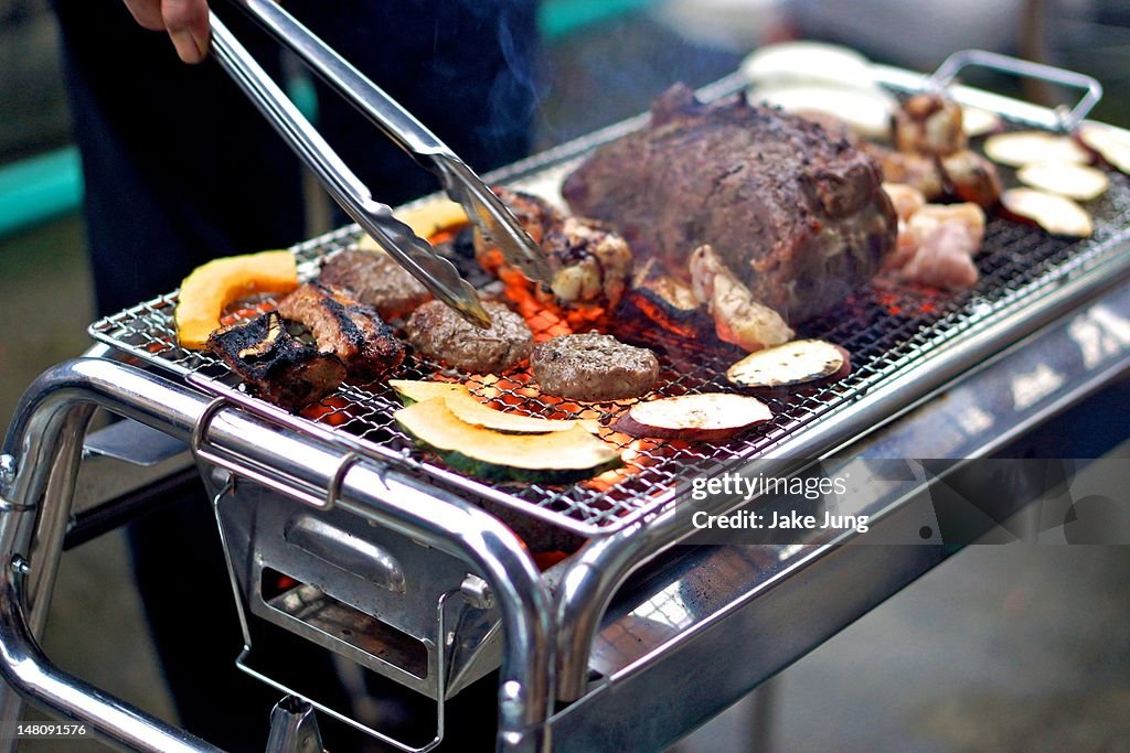 Man using tongs to tend to Japanese barbecue