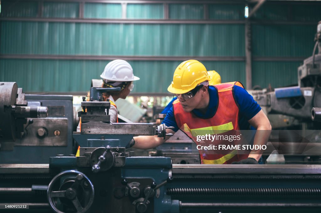 A group of factory workers are using factory lathes to work in the factory, and there is a strict patrol by a female engineer.