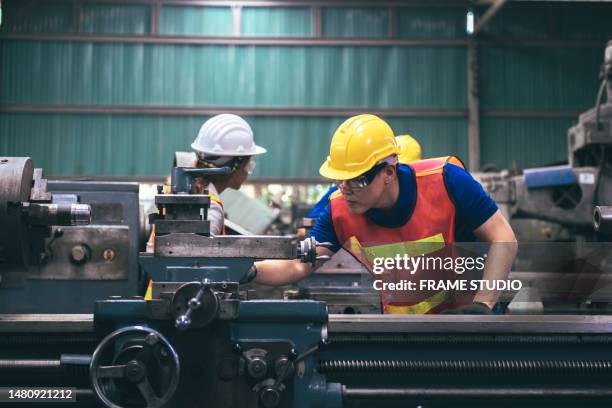 a group of factory workers are using factory lathes to work in the factory, and there is a strict patrol by a female engineer. - industrial labourer stock pictures, royalty-free photos & images