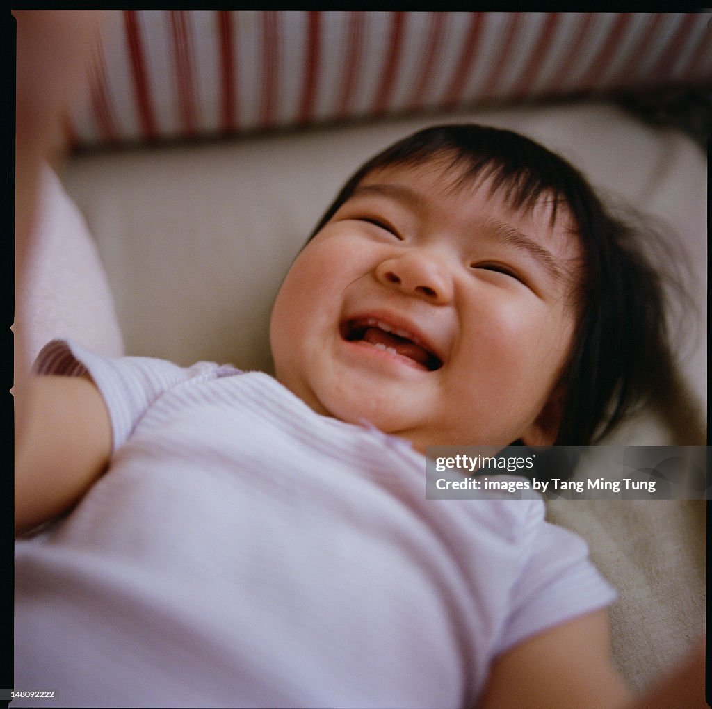 Cheerful baby lying on bed