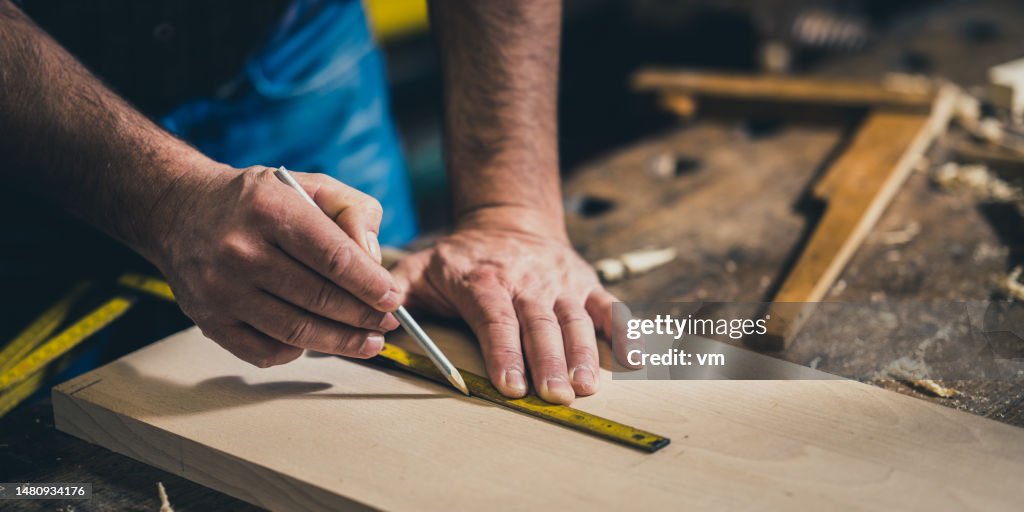 Tischler vermisst Holz mit Messgerät