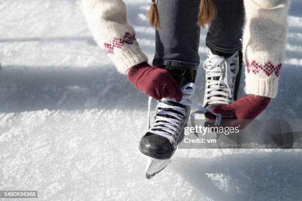woman tying ice skate shoelaces - patim de gelo imagens e fotografias de stock