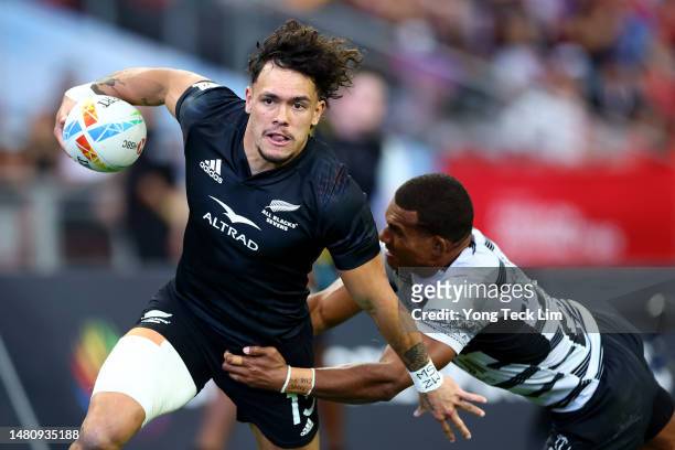 Moses Leo of New Zealand runs with the ball for a try against Suli Volivolituevei of Fiji in their cup semifinal match during the HSBC Singapore...