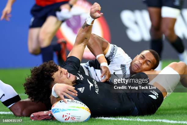 Moses Leo of New Zealand scores a try against Suli Volivolituevei of Fiji in their cup semifinal match during the HSBC Singapore Rugby Sevens at the...