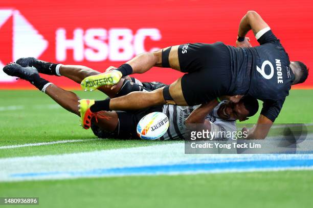 Joseva Talacolo of Fiji scores a try against Amanaki Nicole and Regan Ware of New Zealand in their cup semifinal match during the HSBC Singapore...