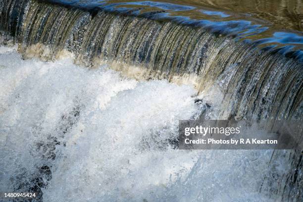 water cascading down a weir in bright sunshine - overflowing river stock pictures, royalty-free photos & images