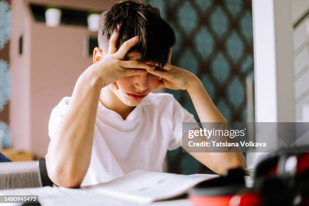 13 years boy studying at desk, head in hands - 14 15 years fotografías e imágenes de stock