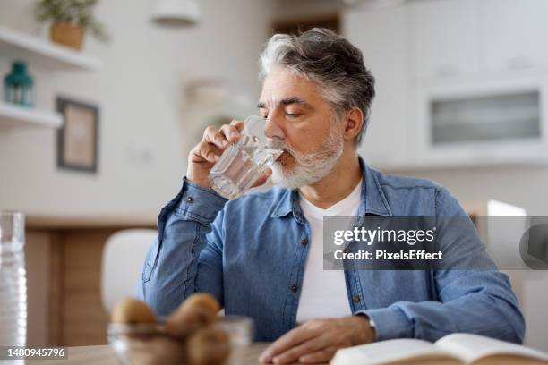 mann trinkt wasser zu hause - wasser trinken zu hause stock-fotos und bilder