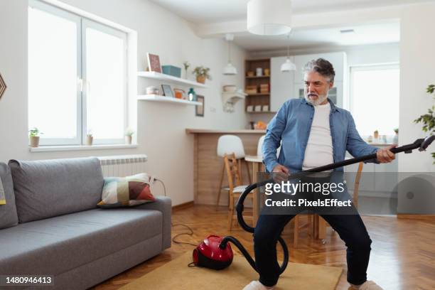 dancing happily with a vacuum cleaner - huishoudelijk werk stockfoto's en -beelden