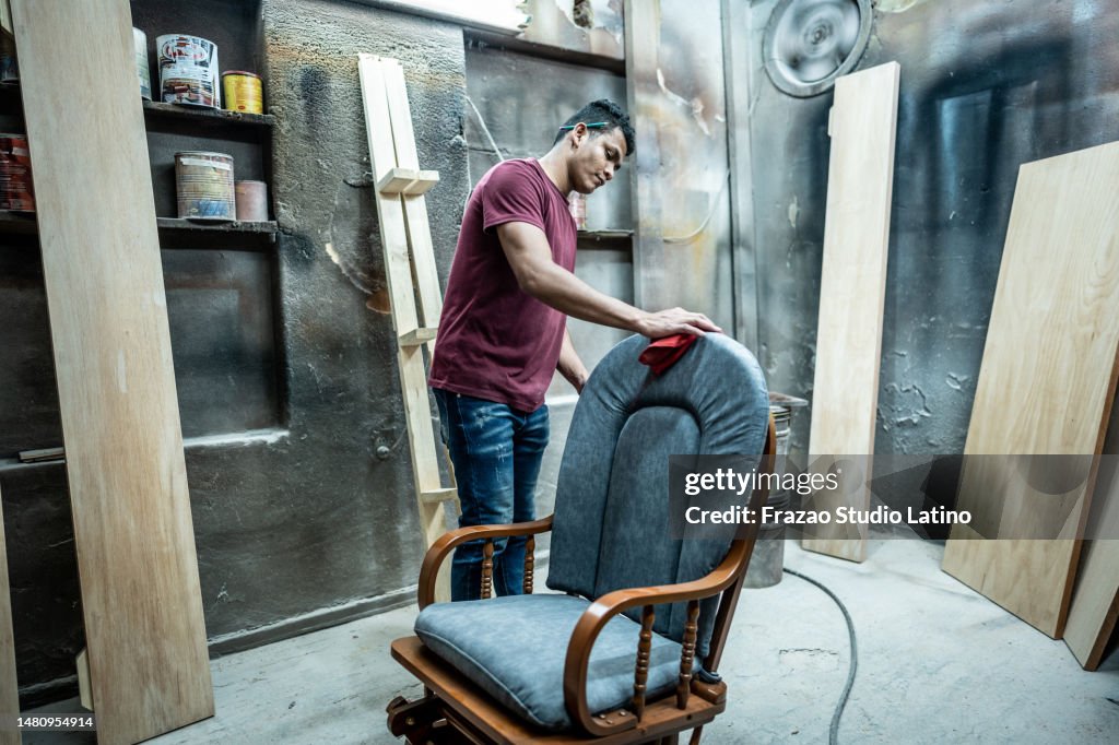 Young man cleaning a chair at carpentry workshop