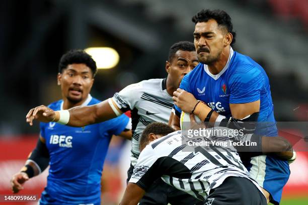 Tuna Tuitama of Samoa runs with the ball against Viwa Naduvalo and Iowane Teba of Fiji in their bronze final match during the HSBC Singapore Rugby...