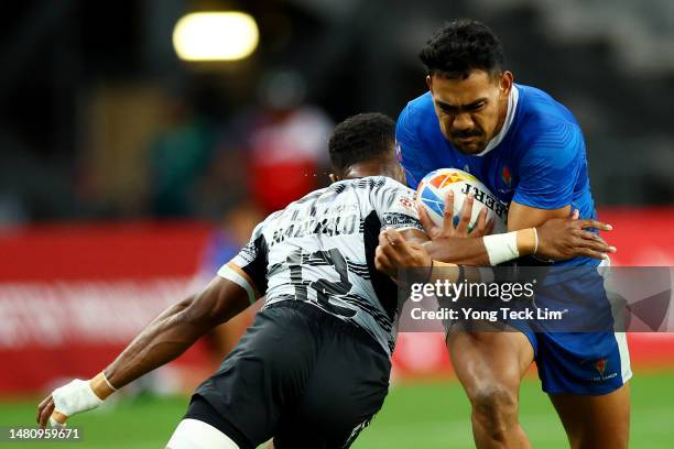 Tuna Tuitama of Samoa runs with the ball against Viwa Naduvalo of Fiji in their bronze final match during the HSBC Singapore Rugby Sevens at the...