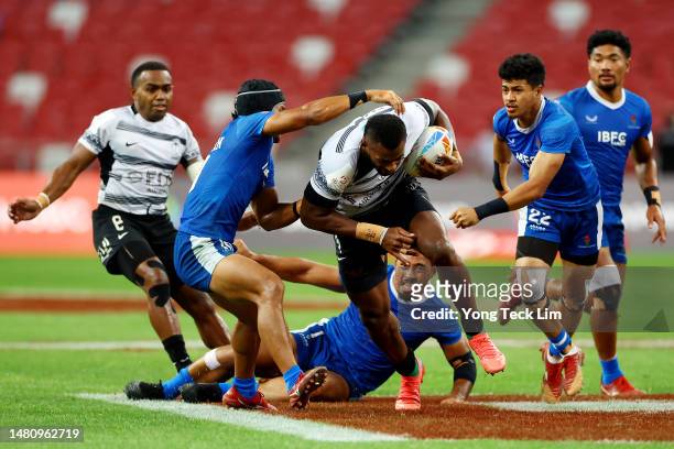 Sevuloni Mocenacagi of Fiji runs with the ball against Paul Scanlan of Samoa in their bronze final match during the HSBC Singapore Rugby Sevens at...