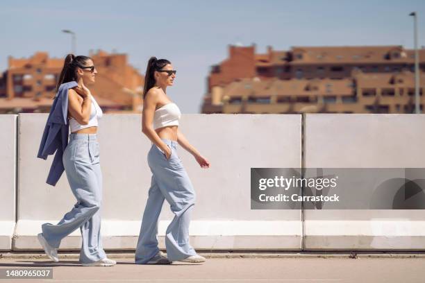 twin sisters on a sunny day wearing sunglasses in the city - identical twin stock pictures, royalty-free photos & images