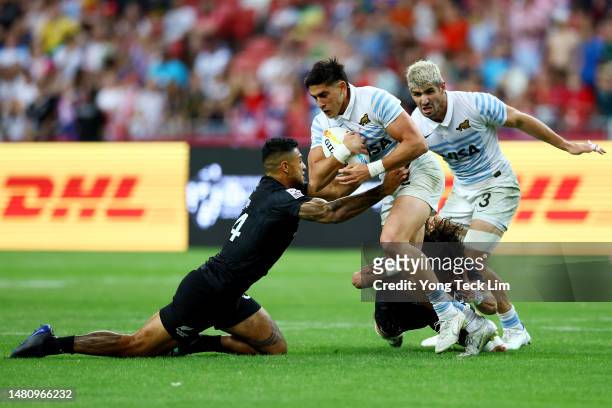 Santiago Vera Feld of Argentina is tackled by Regan Ware and Moses Leo of New Zealand in their cup final match during the HSBC Singapore Rugby Sevens...