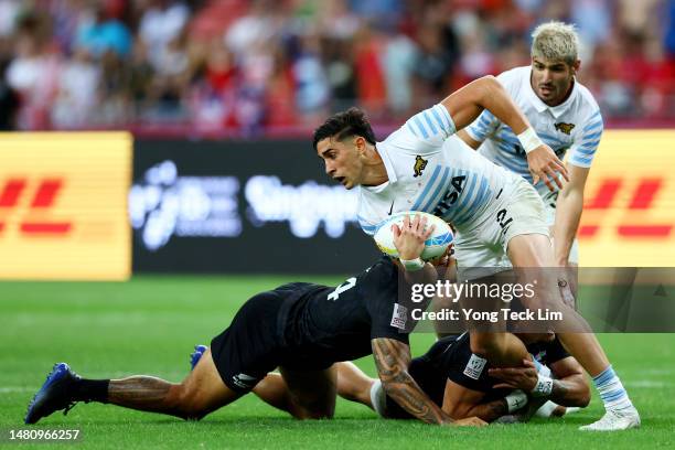 Santiago Vera Feld of Argentina is tackled by Regan Ware and Moses Leo of New Zealand in their cup final match during the HSBC Singapore Rugby Sevens...