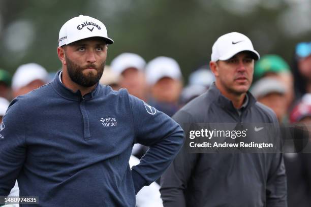 Jon Rahm of Spain and Brooks Koepka of the United States look on from the eighth tee during the continuation of the weather delayed third round of...