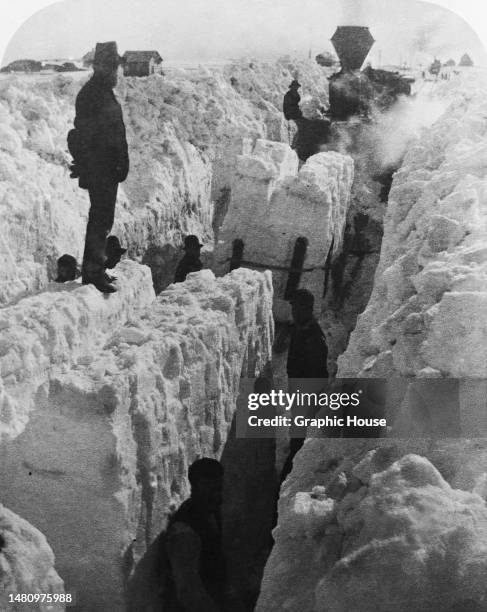 Stereoscopic image showing blocks of snow being removed in an attempt to clear a path of a steam locomotive as the region suffered what became known...