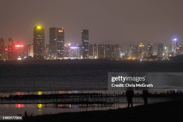 People stand on the beach against the skyline of Chinese city Xiamen on April 09, 2023 in Kinmen, Taiwan. Kinmen, an island in the Taiwan strait that...