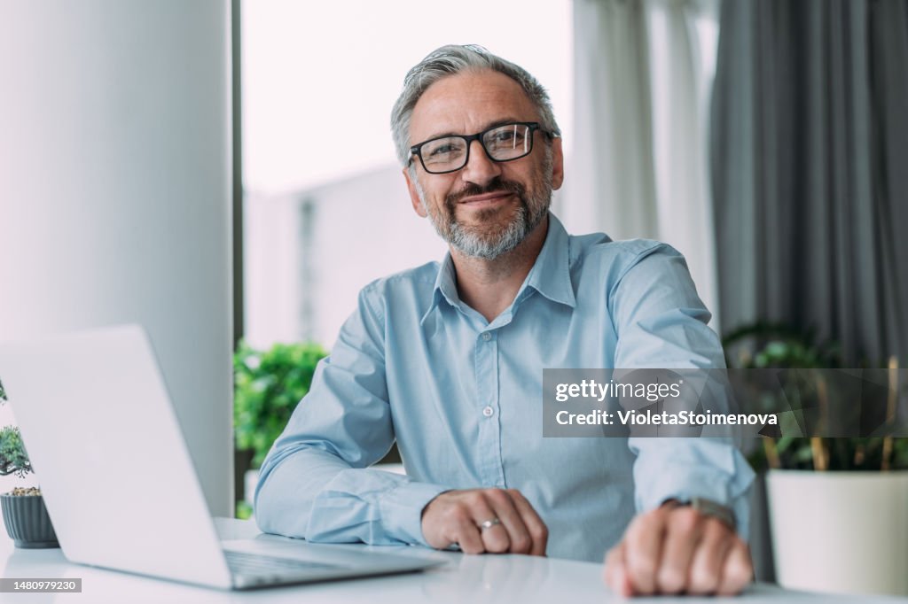 Successful businessman in modern office working on laptop.